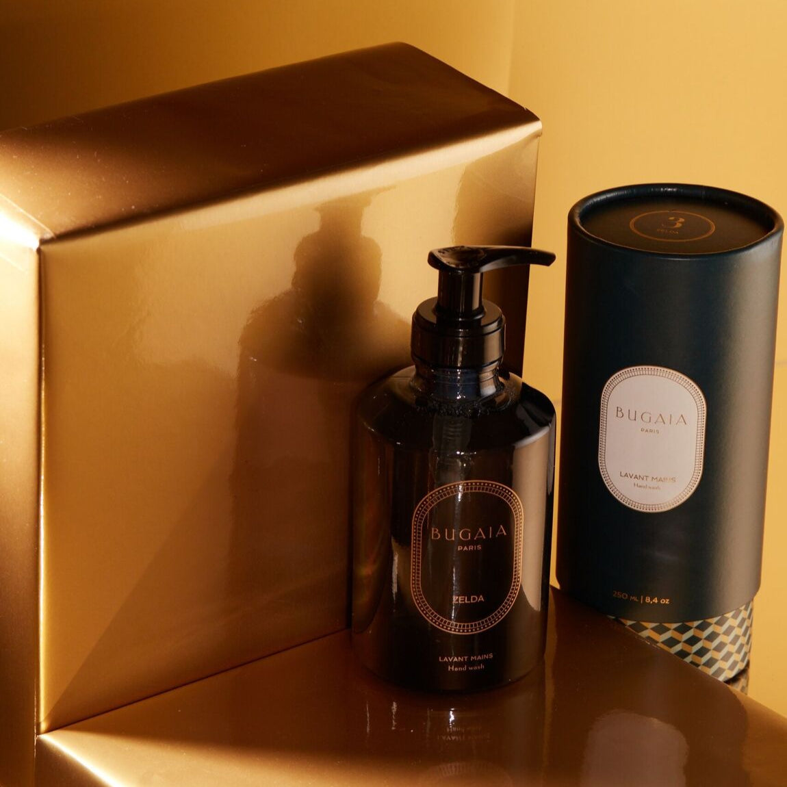 Elegantiškas ZELDA prabangus rankų muilas 250 ml talpos buteliuke su dozatoriumi. Stilingas dizainas su subtiliomis gėlių ir medienos natomis, puikiai tinkantis vonios ar virtuvės interjerui. Fone – švarus, modernus paviršius.