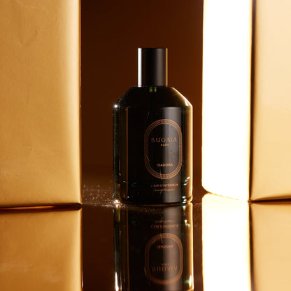 BUGAIA purškiamas namų kvapas „Isadora“ 100 ml Art Deco stiliaus stikliniame buteliuke su purkštuku. Elegantiškas dizainas perteikia šiltų medienos ir rytietiškų prieskonių kvapų atmosferą. Fotografuota moderniame interjere arba ant šviesaus tekstilės paviršiaus.
