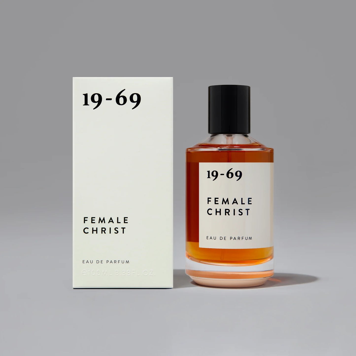 19-69 Female Christ“ kvepalų buteliukas – gintaro spalvos stiklas su juodu dangteliu ir minimalistine etikete.